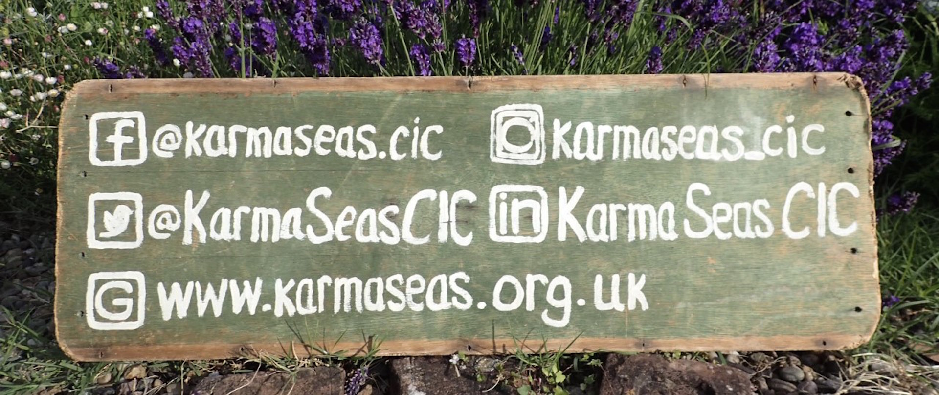a wooden sign with karma seas contact details painted on it